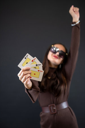 Young pretty woman with playing cards ace posign isolated on black background. Gambling conceptの写真素材