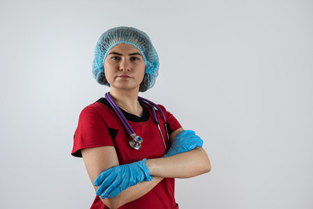 Portrait of young caucasian female nurse or doctor wear red uniform, blue gloves with stethoscope. Medical conceptの写真素材