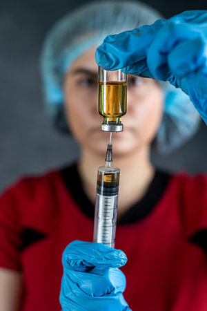 Caucasian healthcare worker woman nurse with syringe and ampoule, preparing vaccine. Medicine and drug concept.の写真素材