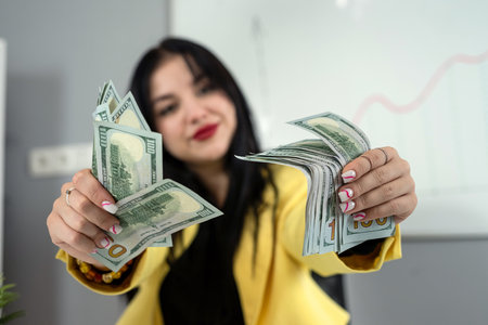 Young woman business worker counting dollars with finance documents and laptop at office. Payment salary and incomeの写真素材