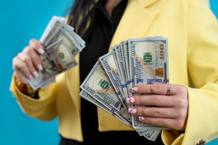 Cheerful young lady hold dollar cash isolated on blue.  Financial business concept, betting and winningの写真素材