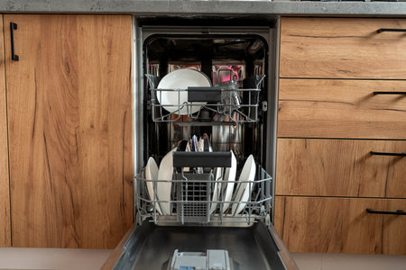 Open door of built-in dishwasher with clean  plates and dishes at kitchen. Houseworkの写真素材