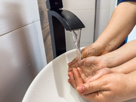 mother washes the child's hands with soap in the bathroom sink. The concept of cleanliness and skin careの写真素材