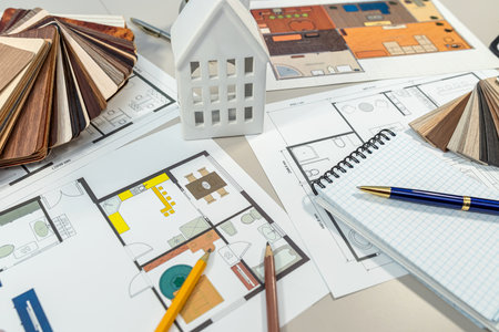 On the table, there is a detailed floor plan of a house that showcases its layout and design features, serving as an essential project toolの写真素材