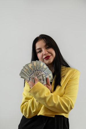 Happy pretty business woman in suit holding money isolated on grey.の写真素材