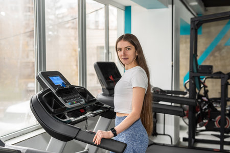 portrait of caucasian fit female athlete stand near machine treadmill and rest after exercise at the...