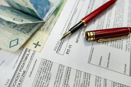 PLN zloty money on polish tax form PIT 11, with pen and calculator. Accounting concept.の写真素材
