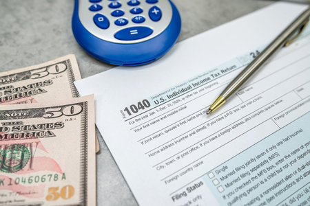 US 1040 form or US Individual income pen calculator dollar on desk. Accounting documents taxation...