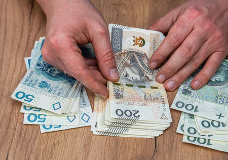 Man holding many polish zloty banknote wooden desk background. Financial conceptの写真素材