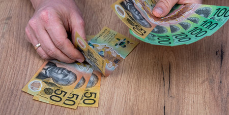 business man holding Australian Dollar AUD banknotes on wooden desk background. Financial saving conceptの写真素材