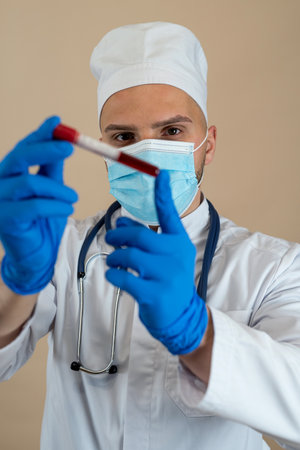 young caucasian doctor in protective uniform mask and gloves hold testing tube with blood isolated. Healthcare conceptの写真素材