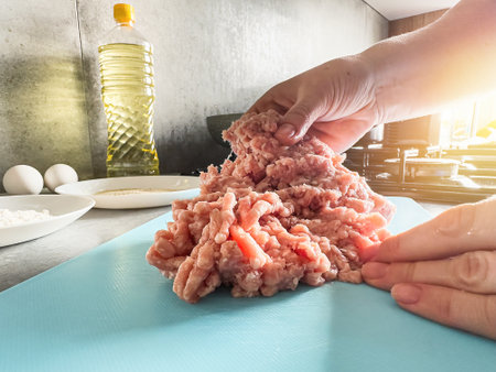 woman in the kitchen prepares delicious homemade cutlets or pelmeni from raw minced meat.の写真素材