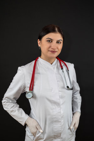 Caucasian beautiful female doctor in white coat with stethoscope, isolated on black studio shootの写真素材