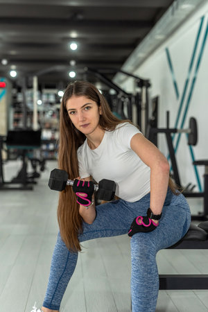 Slim caucasian girl doing biceps curls with dumbbell at the gym. Healthy lifestyleの写真素材