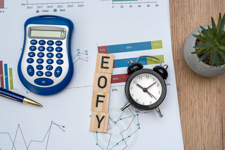 focus on wooden blocks EOFY End of Financial Year with pen calculator and business diagraph paperwork. Taxation conceptの写真素材