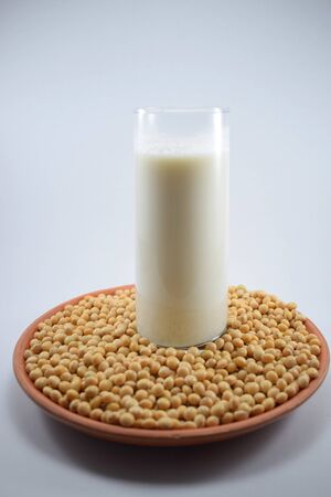Glass of soy milk in the middle of a bowl of soy beansの写真素材