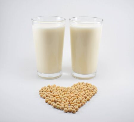 Two glasses of soy milk and soy beans forming a heartの写真素材