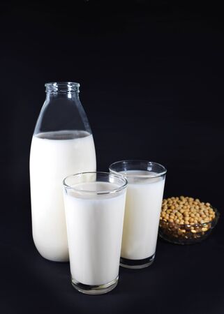 Bottle and two glasses of soy milk, bowl with soy beansの写真素材