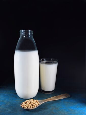 Bottle and glass of soy milk, spoon with soy beansの写真素材