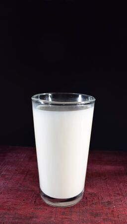 Glass of milk on wooden table and black backgroundの写真素材