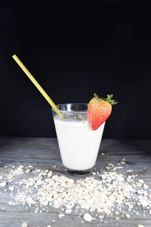 Oatmeal milkshake with strawberry on wooden table and black backgroundの写真素材