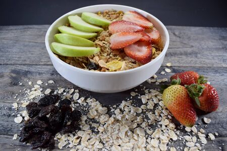 Bowl with cereal, oats, raisins, apple and strawberriesの写真素材