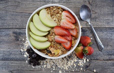 Bowl with cereal, oats, raisins, apple and strawberryの写真素材