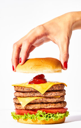 quadruple steak burger with cheddar and lettuce held in one handの写真素材