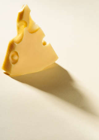 cheese with holes isolated on color background cut into triangular shapeの写真素材