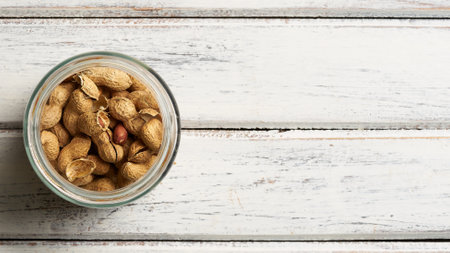 peanuts with shell inside jar on wooden table