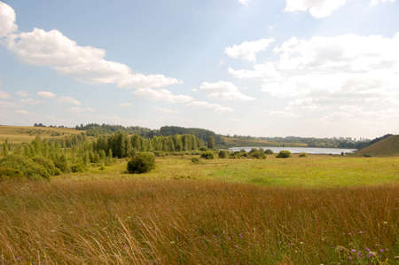 Autumn glade with a lake, forest and cloudsの写真素材