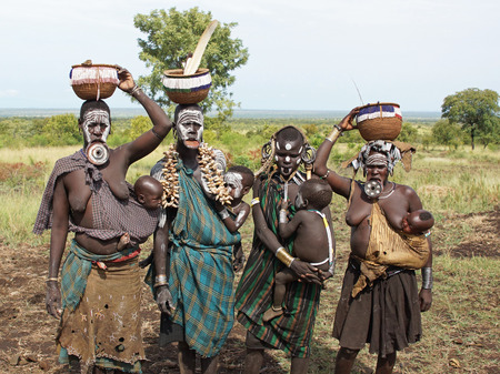 JINKA, ETHIOPIA - NOVEMBER 21, 2014: Mursi women with traditional lip plate and children on November...
