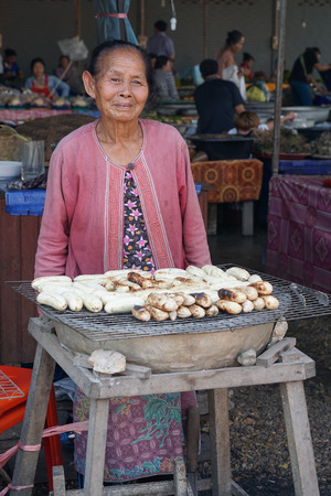 VIENTIANE, LAOS - FEBRUARY 19, 2016:  Old woman selling grilled bananas on a market on February 19, 2016 in Vientiane, Laos, Asiaのeditorial素材