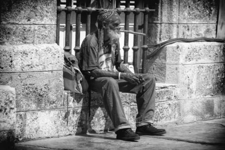 HAVANA, CUBA - FEBRUARY 23, 2010: Old man smoking a big cigar while sitting on the street on February 23, 2010 in Havana, Cuba, Caribbeanのeditorial素材