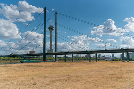 DUESSELDORF, GERMANY - AUGUST 10, 2018: Drought in Germany, low water of the Rhine river in Duesseldorf with bridge and TV tower on August 10, 2018 in Germanyのeditorial素材