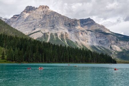 FIELD, CANADA - AUGUST 14, 2019: Tourists are canoeing on Emerald lake in front of the magnificent backdrop of the Rocky Mountains on August 14, 2019 in the Yoho National Park, British Columbia, Canadaのeditorial素材