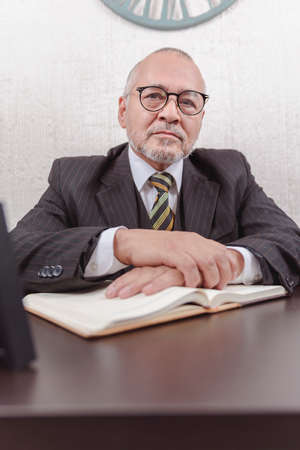 Closeup on a school teacher sitting at his desk taking notes