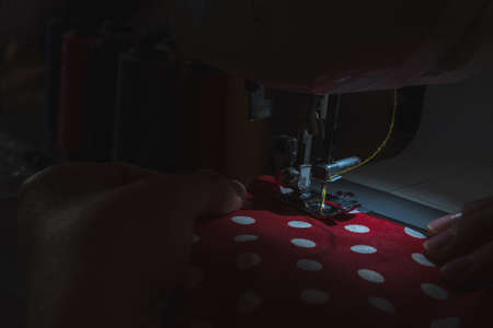 A sewing machine is shown up close only illuminated with its work lightの写真素材