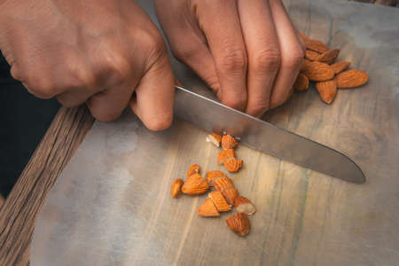 Close-up of a person with kitchen knife cutting almonds in his kitchenの写真素材