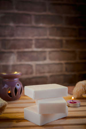 Beautiful spa composition with natural soaps with scented candles and bathroom accessories in a romantic setting for a cleansing concept. There is shallow depth of field and room for text.の写真素材