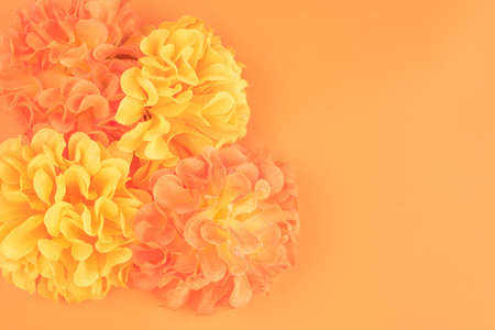 Closeup to some yellow and orange artificial flowers on plain background, there is space for textの写真素材