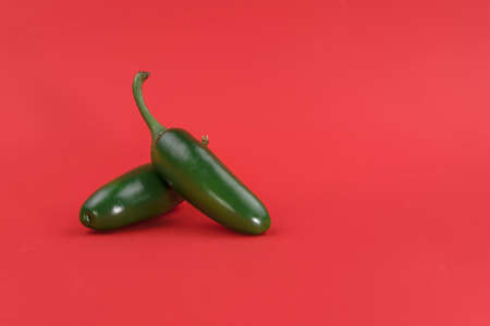 Ripe green chili peppers on a red background, the background has room to add textの写真素材