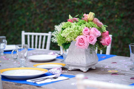 Table in the garden with blue and yellow porcelain plates, with empty crystal glasses and a flower...