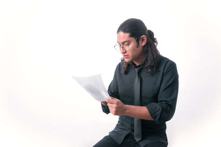 Person on white background. He is reading a sheet of paper and is serious because he doesn't like what is written, he is thinking. White space. Man gesticulating.の写真素材