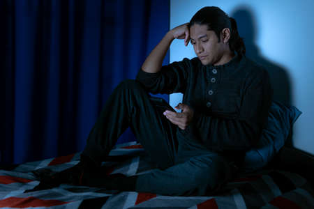 Insomnia, Depressed man sitting up in bed at night, he can't sleep from insomnia