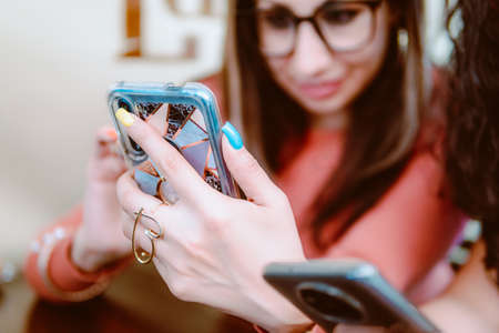 Two girls are sitting and looking at a cell phone, they are looking closely at their cell phones.の写真素材