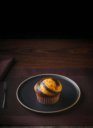 Vanilla Muffin with chocolate marbled on brown paper isolated on a thin plate on a nice table, fine pastries, Copy spaceの写真素材
