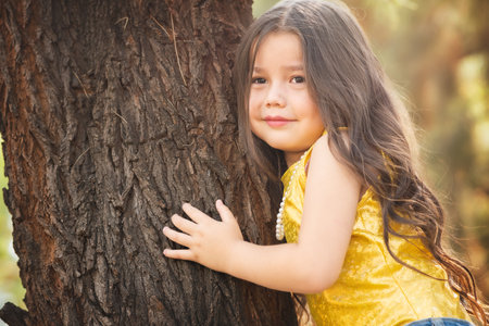 Blonde preschool girl hugging a tree. Expressions of happiness. Model girl. children's day theme. International tree dayの写真素材