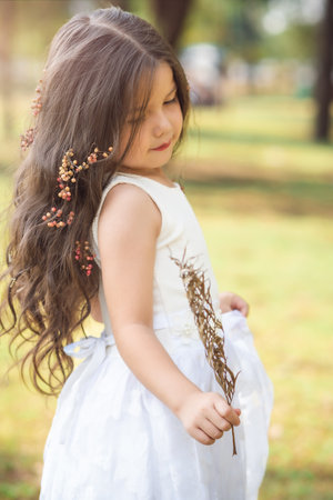 Girl in white dress and princess crown plays in the forest as in a fairy tale, copy space, children's day theme.の写真素材