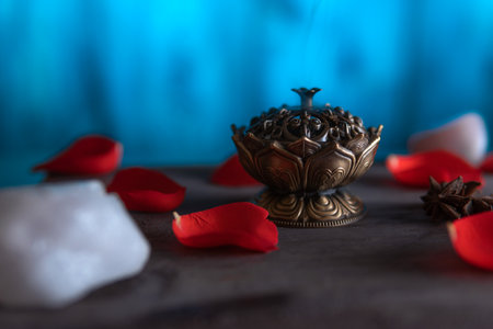 Close-up of a beautiful incense burner on a wooden table with quartz and petals, copy paste, on a blue background. spiritual themes and esoteric ritualsの写真素材